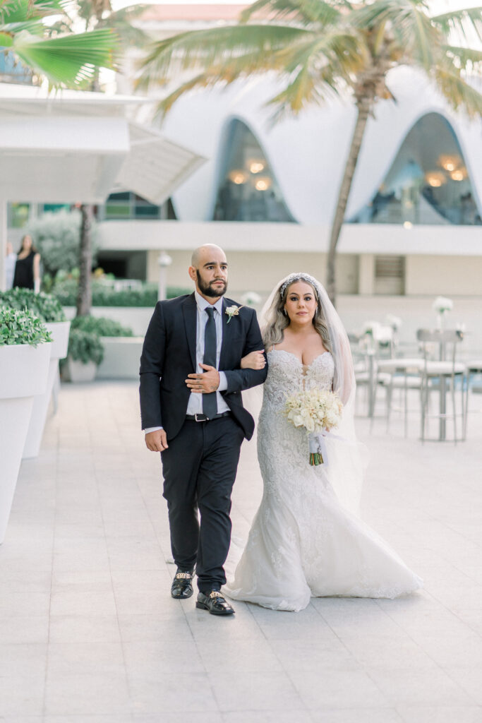 Bride walking to the ceremony accompanied by a man in tuxedo