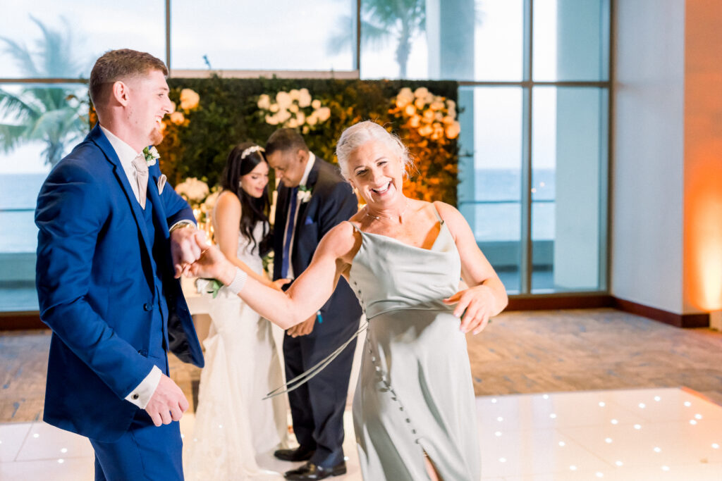 groom dancing with his mom while bride dances with her dad on the background